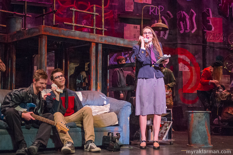 Pioneer Theatre Guild: Rent | Roger Davis and Mark Cohen (Nathan Stout and Remington Reackhof) laugh as they listen to a voicemail from Mark’s ridiculously forthright mother, Mrs. Cohen (Emily Uhlmann).