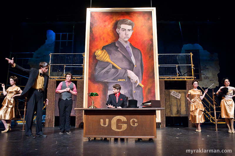 Pioneer Theatre Guild: Urinetown | The office of Caldwell B. Cladwell, the money-grubbing, cold-hearted, Hobbesian president and owner of Urine Good Company (UGC on the NASDAQ). Cladwell’s portrait was expertly painted by Raye Evrard and Elayne Fivenson, with David Zinn. 